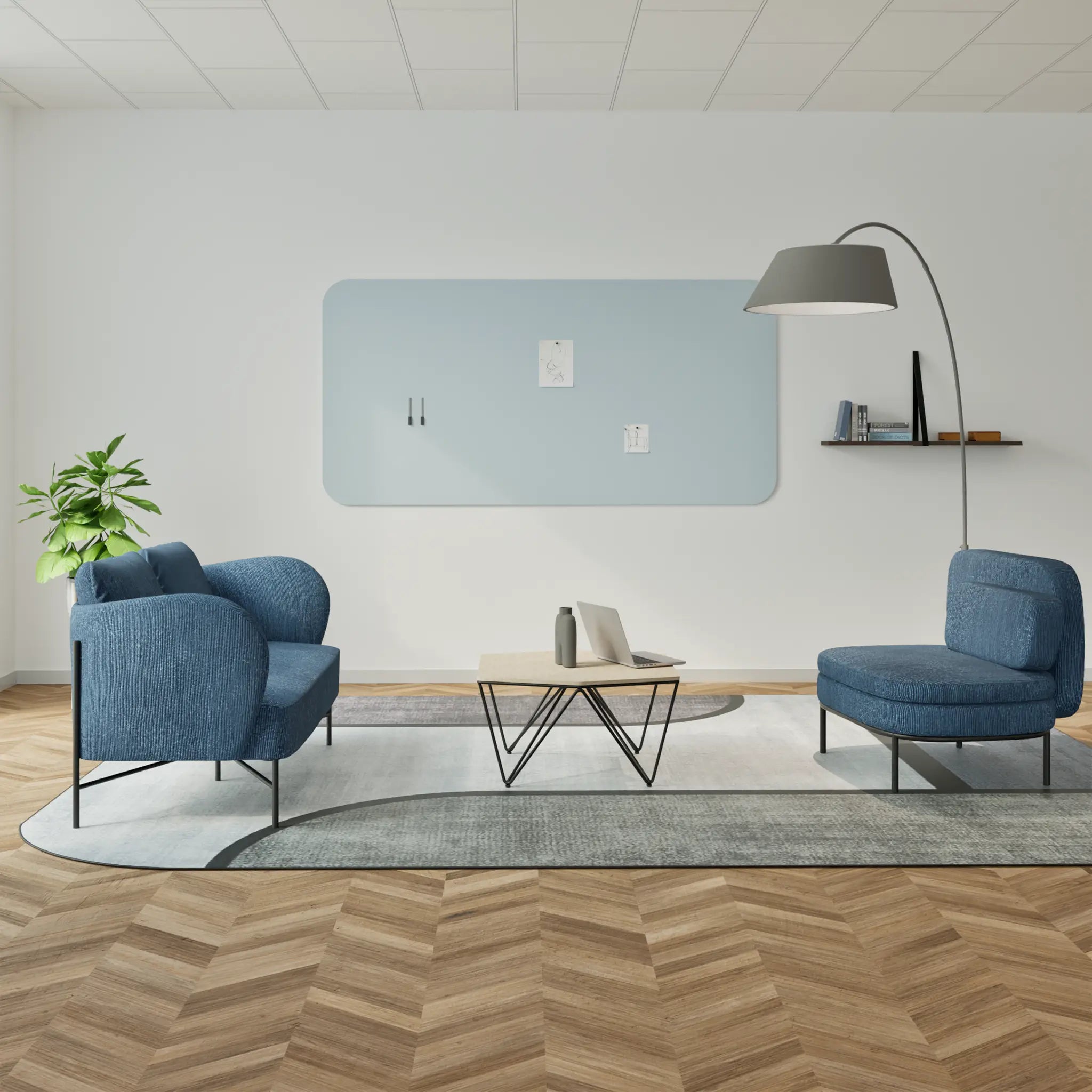 Modern office lounge with blue chairs, coffee table, Chameleon Curve frameless whiteboard, wood herringbone floor, and plant.