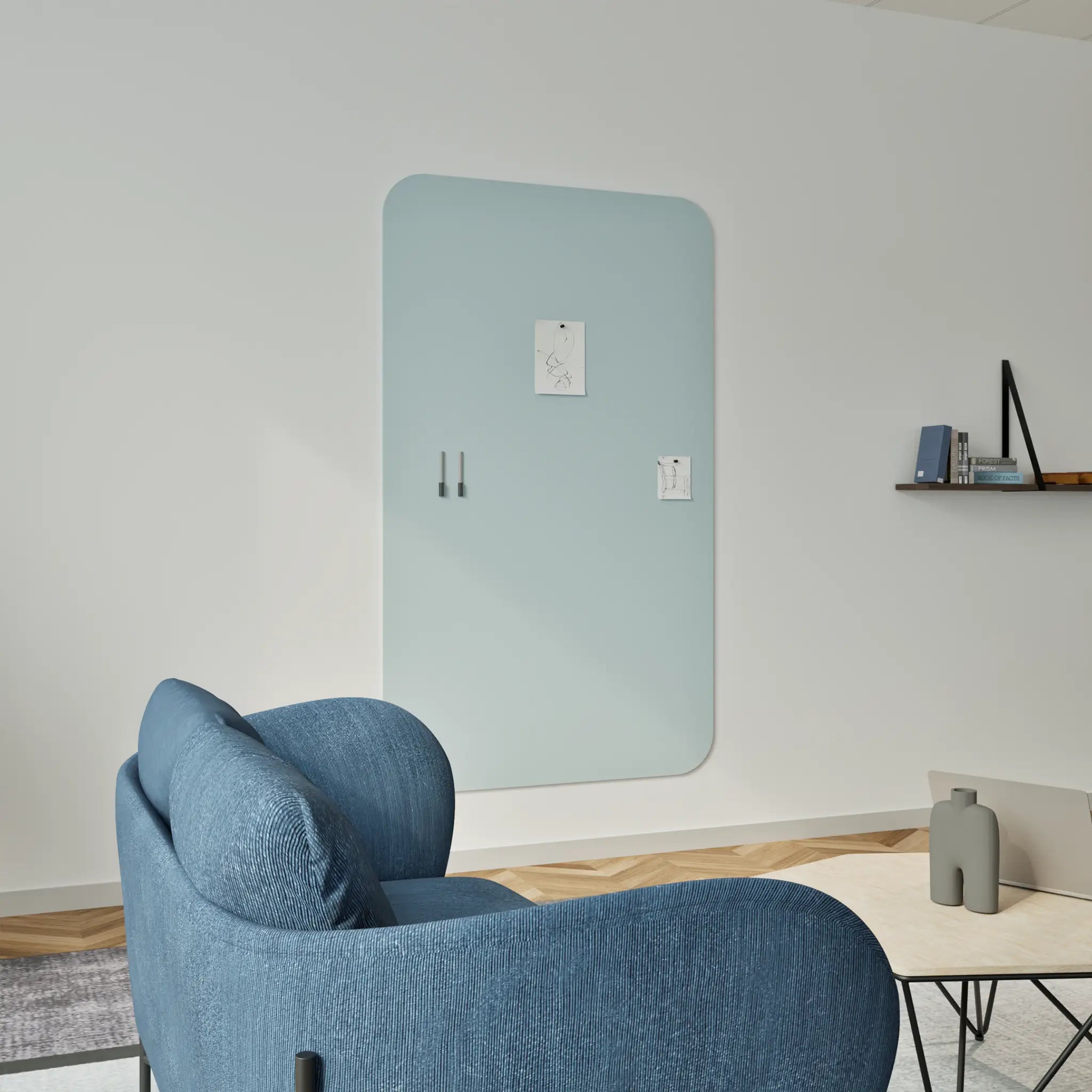 Modern living room with blue chair, wood coffee table, books, and Chameleon Curve pastel blue whiteboard on a white wall.