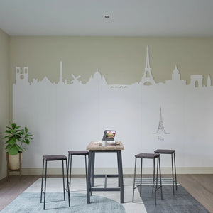 Modern workspace with a high table, bar stools, laptop, plant, and Chameleon Custom Whiteboard Wall with Paris skyline design.