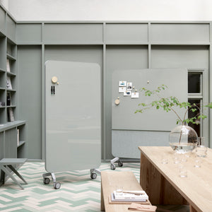 Modern office with sage green walls, Lintex Mood Fabric magnetic mobile glass whiteboards, wood table, greenery, chevron floors.