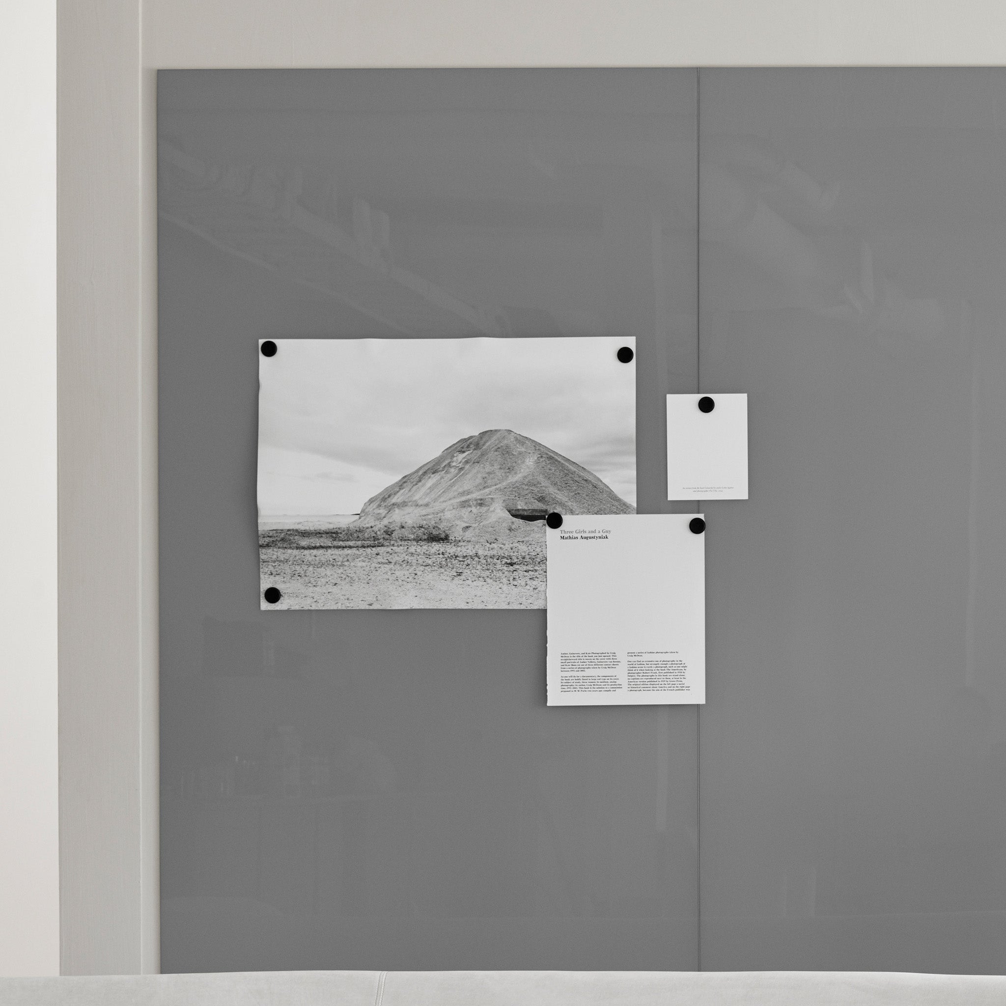 Showcasing Lintex Mood Spaces magnetic glass board with three papers—hill photo, square cutout, and text sheet—held by magnets.