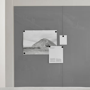 Showcasing Lintex Mood Spaces magnetic glass board with three papers—hill photo, square cutout, and text sheet—held by magnets.