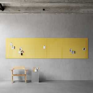 Minimalist office with concrete ceiling, gray walls, yellow Lintex Mood Spaces magnetic glass board, wooden desk, and pen holder.