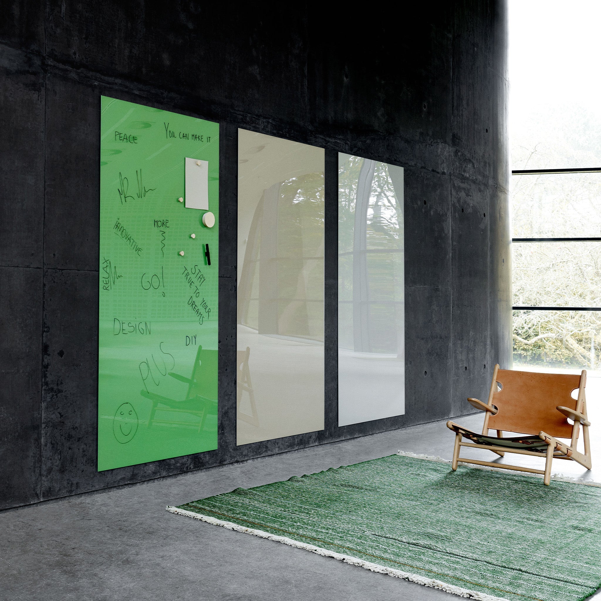 Modern minimalist room with dark walls, large windows, tan leather chair, green rug, and three Lintex Mood Wall magnetic glass boards.