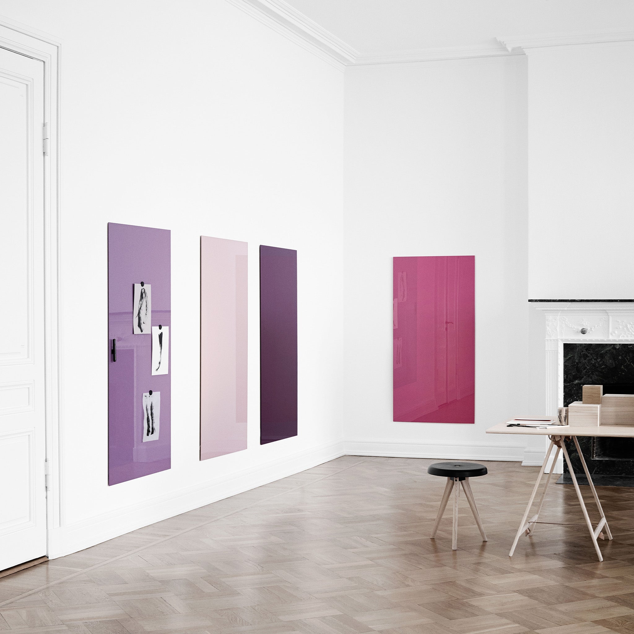 Minimalist room with Lintex Mood Wall panels in purple and pink, light walls, wood floors, black stool, desk, and white fireplace.