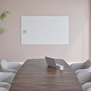 Sleek meeting room with wooden table, gray chairs, open laptop, mug, and Chameleon Frameless VES Magnetic Whiteboard on beige wall.