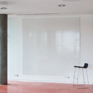 Elevate your workspace with a minimalist room: dry wipe unframed writing wall, tall gray pillar, red floor, and black high chair.