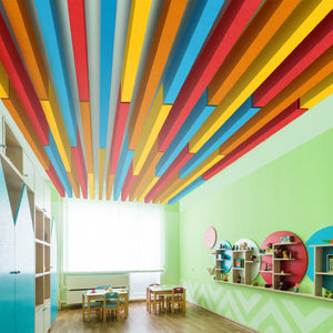 Vibrant classroom with green walls, kid-sized tables, Zen Zone Baffle acoustic panels, and sunlight pouring through large windows.