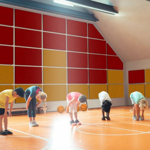 Kids in sportswear stretch on a basketball court with Zen Zone Zen Impacta acoustic panels, highlighting sound-absorbing design.