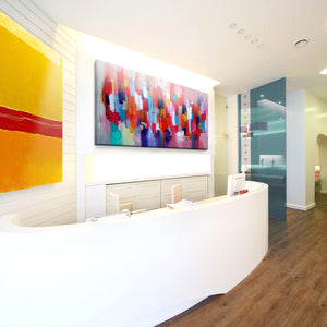 Modern reception with curved white desk, vibrant art, Zen Zone acoustic panels; glass doors in hallway. Stylish sound absorption.