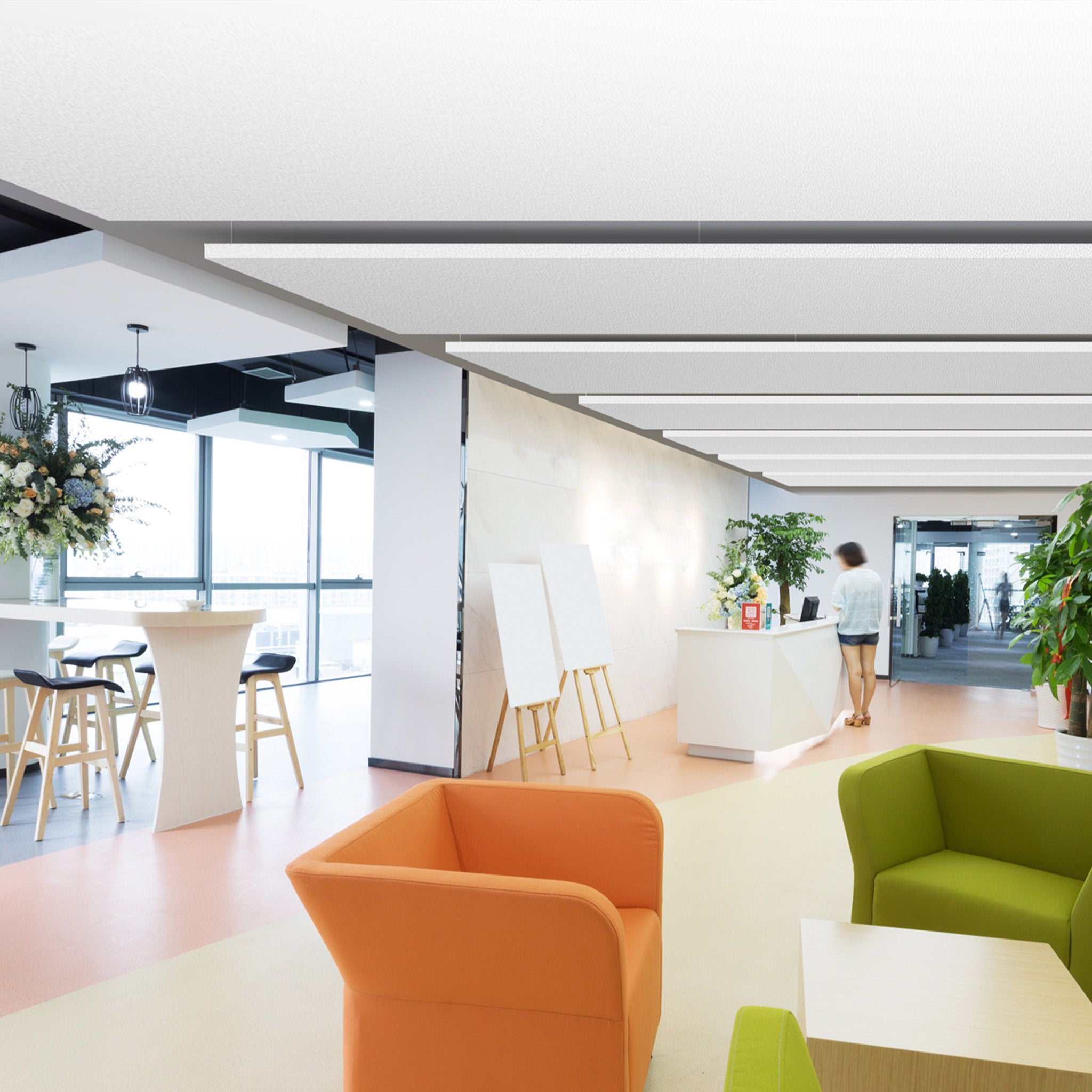 Modern office lobby with Zen Zone Zen Raft acoustic panels, vibrant chairs, lush plants, and sleek reception, filled with daylight.