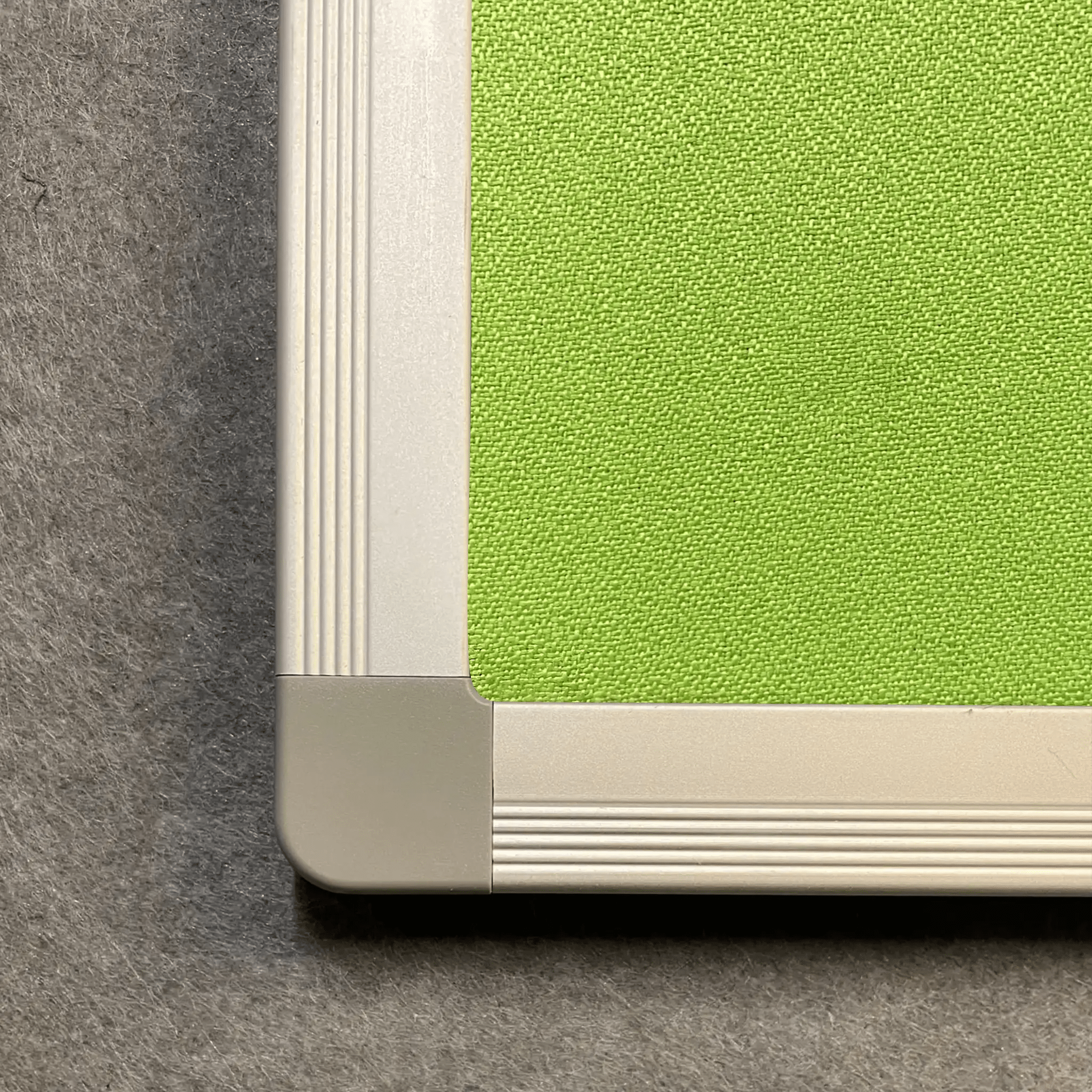 Premium green Premier Camira Lucia aluminium notice board close-up, textured surface, Class B fire rating, grey felt backdrop.