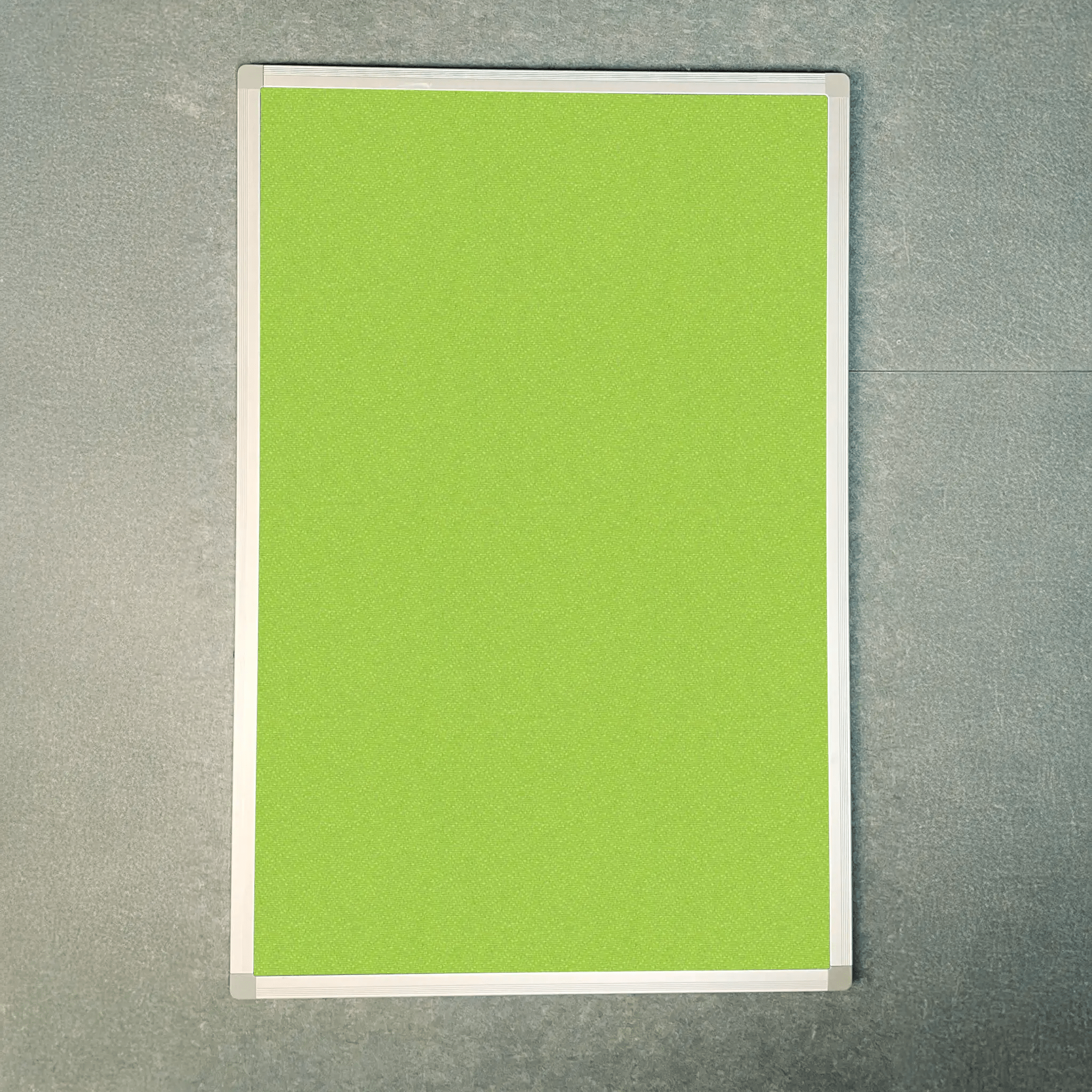 UK-made Premier Camira Lucia green notice board with aluminium frame, Class B fire rated, displayed on a gray wall.
