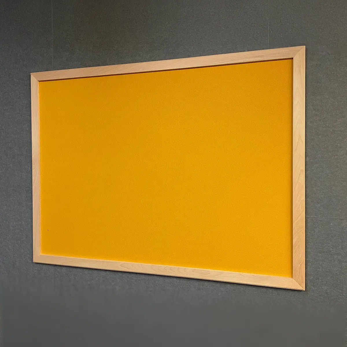 Premier Camira Lucia Notice Board with yellow surface and ash frame on gray wall, ideal for global risk office safety. Class B fire rated.