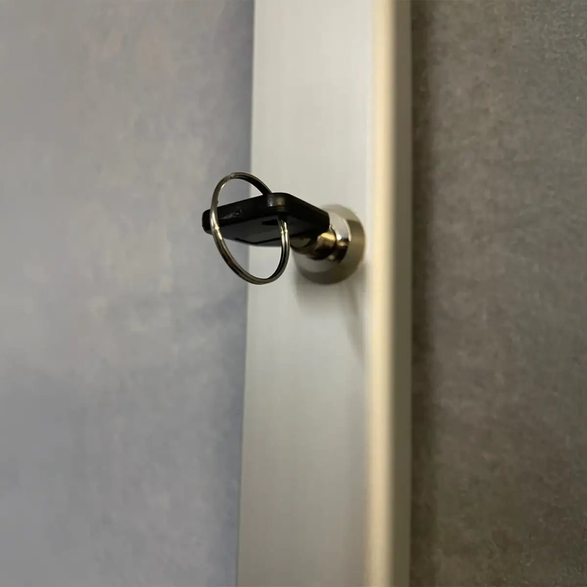 Close-up of a black key unlocking a weatherproof wall-mounted noticeboard, ideal for secure display in high-risk locations worldwide.