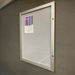Weatherproof noticeboard on gray wall with single flyer—ideal for vital insurance alerts in any high-risk or global work zone.